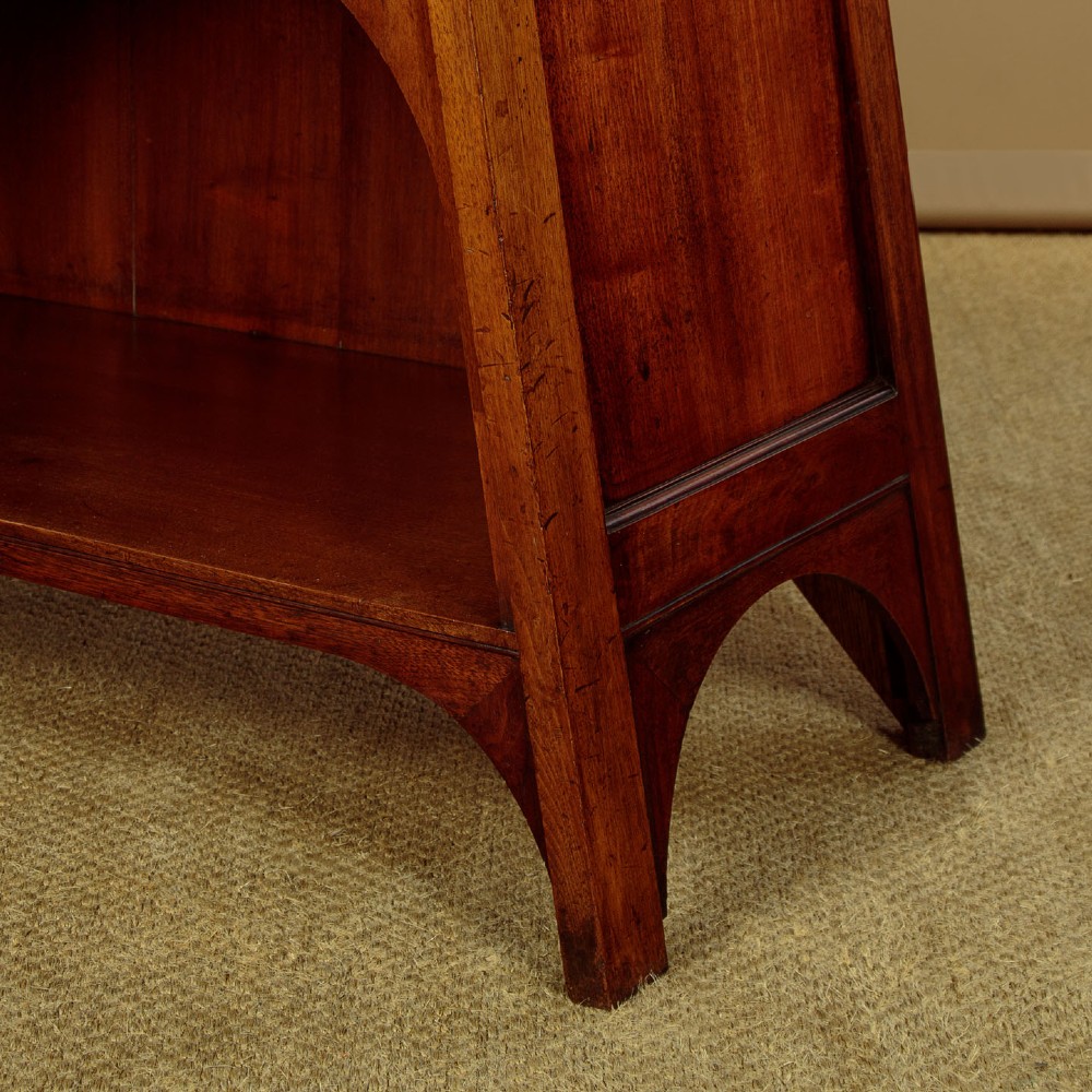 An Arts and Crafts oak side cabinet featuring an upper spindle gallery, arched open shelves, diagonal side struts, and a central cabinet door with leaded glass. View XI