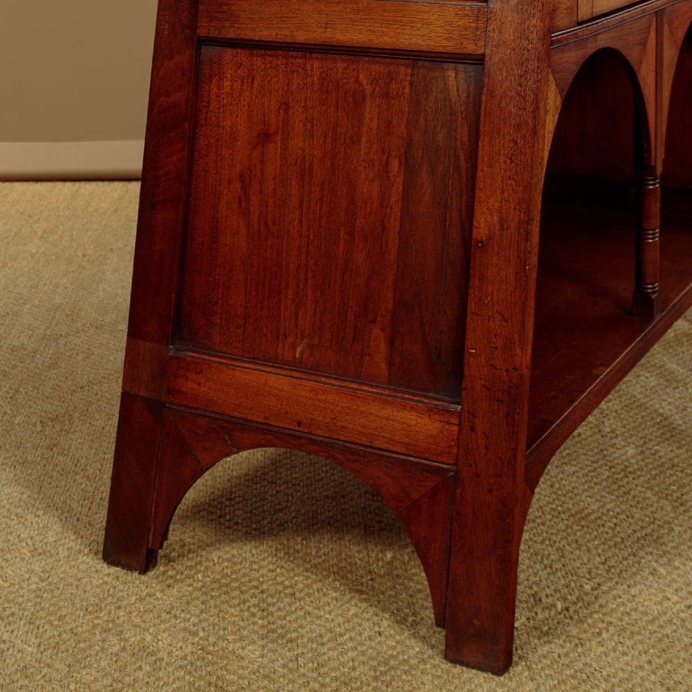 An Arts and Crafts oak side cabinet featuring an upper spindle gallery, arched open shelves, diagonal side struts, and a central cabinet door with leaded glass. View XII
