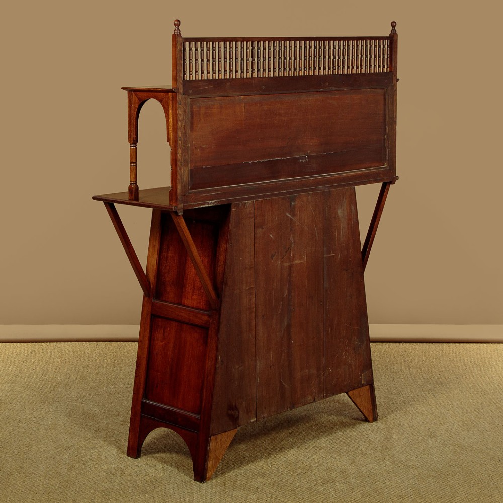An Arts and Crafts oak side cabinet featuring an upper spindle gallery, arched open shelves, diagonal side struts, and a central cabinet door with leaded glass. View XIII