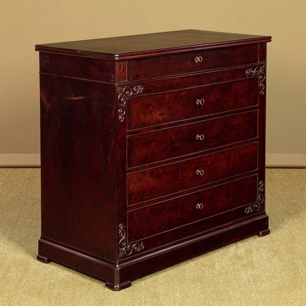 A mid-19th century French Louis Philippe mahogany chest of drawers featuring five stacked drawers, polished dark timber finish, brass keyhole escutcheons, and foliate carvings framing the corners. View III