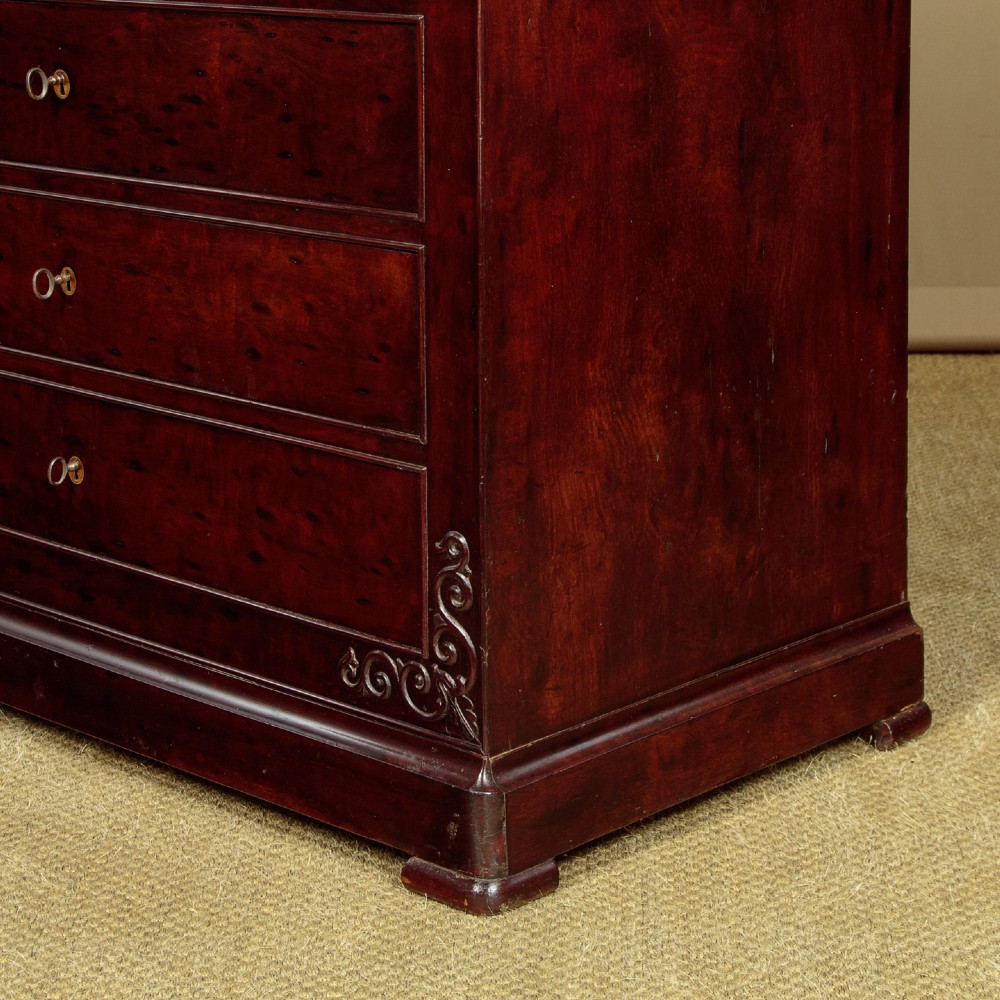 A mid-19th century French Louis Philippe mahogany chest of drawers featuring five stacked drawers, polished dark timber finish, brass keyhole escutcheons, and foliate carvings framing the corners. View IX