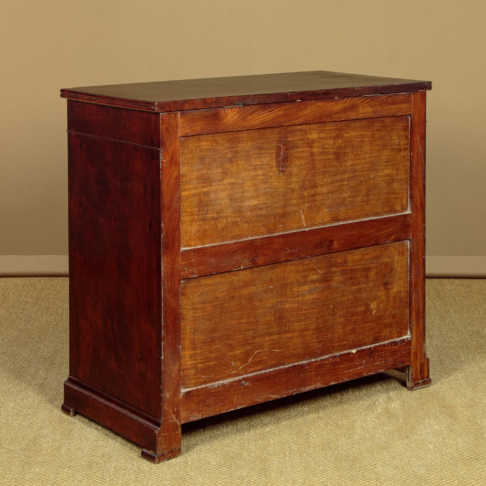 A mid-19th century French Louis Philippe mahogany chest of drawers featuring five stacked drawers, polished dark timber finish, brass keyhole escutcheons, and foliate carvings framing the corners. View X