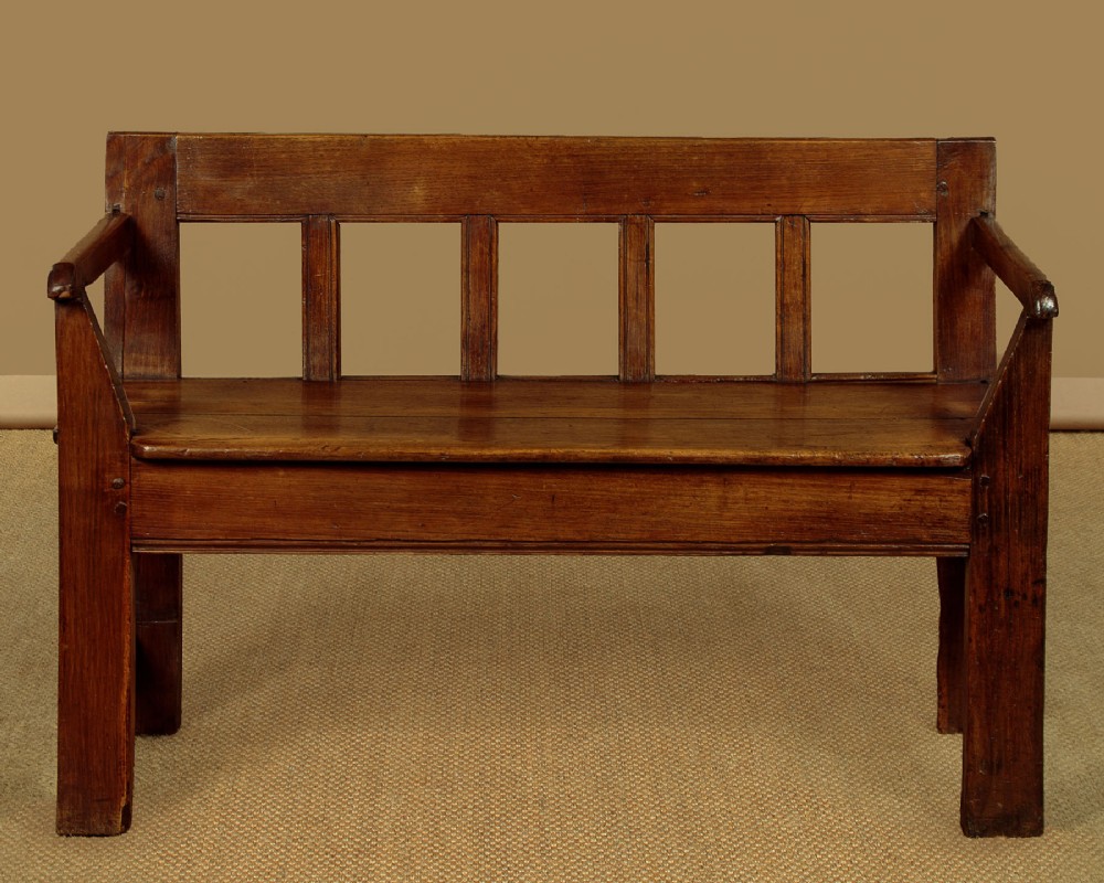A small antique warm brown oak hall bench featuring a slatted open backrest, straight armrests, and a solid plank seat. View II