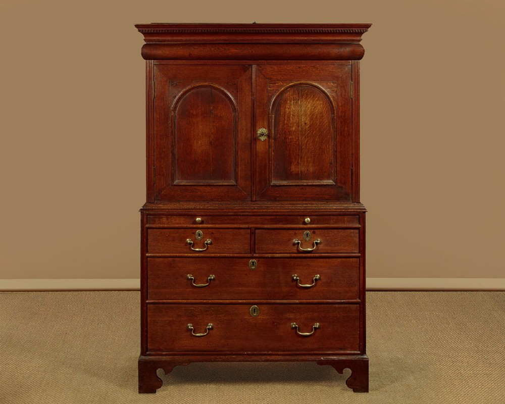 An early 18th-century oak cabinet on chest featuring twin panelled doors opening to internal drawers and pigeonholes above a chest of drawers with brass handles. View III