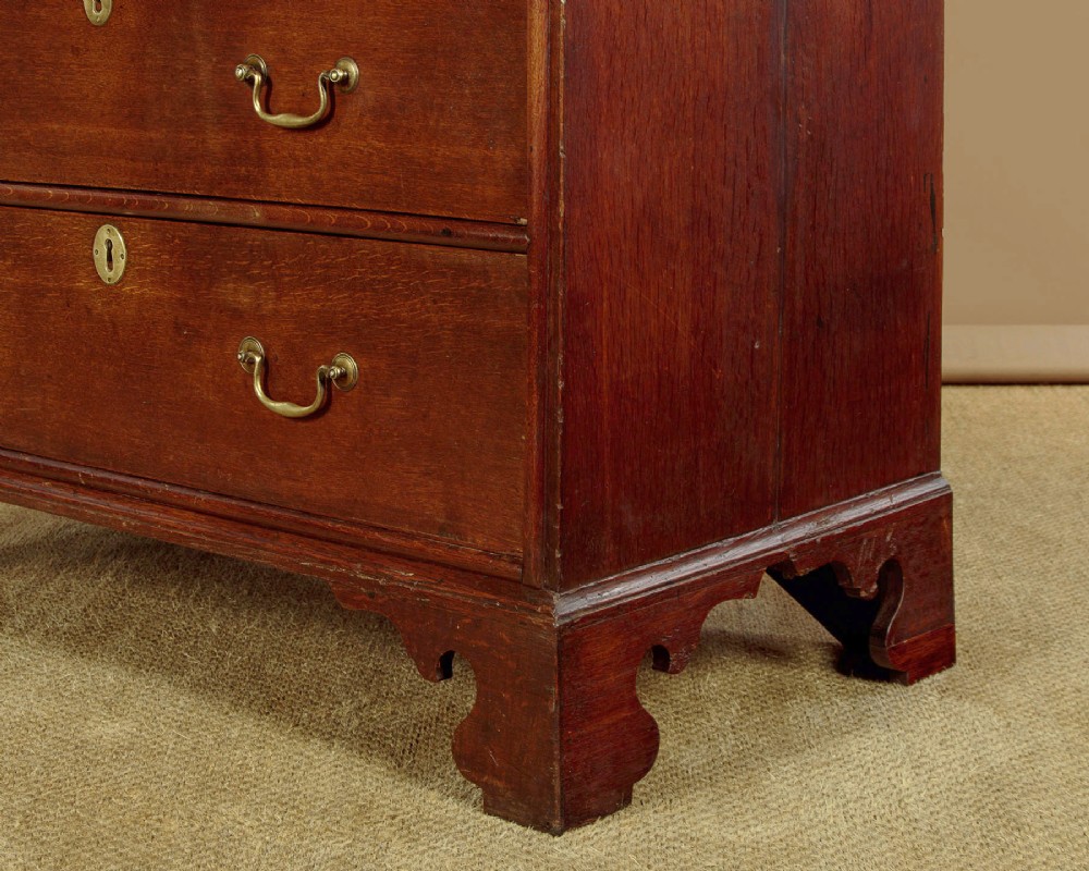 An early 18th-century oak cabinet on chest featuring twin panelled doors opening to internal drawers and pigeonholes above a chest of drawers with brass handles. View XV