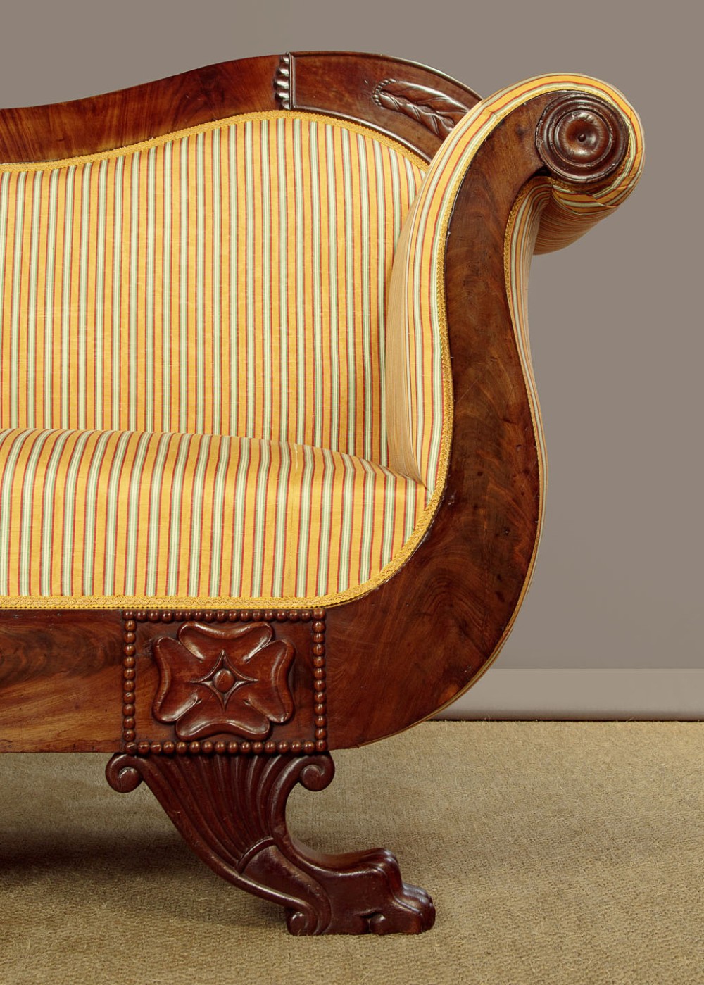A Regency mahogany scroll end couch featuring swept arms, carved anthemion accents, and yellow striped fabric upholstery. View V