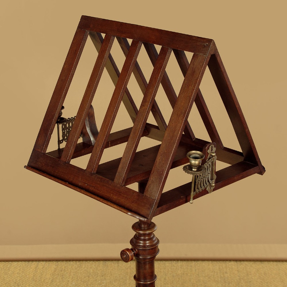 An antique dark mahogany duet music stand with a double-sided slatted rack, twin adjustable brass candle sconces, and a tripod base. View V