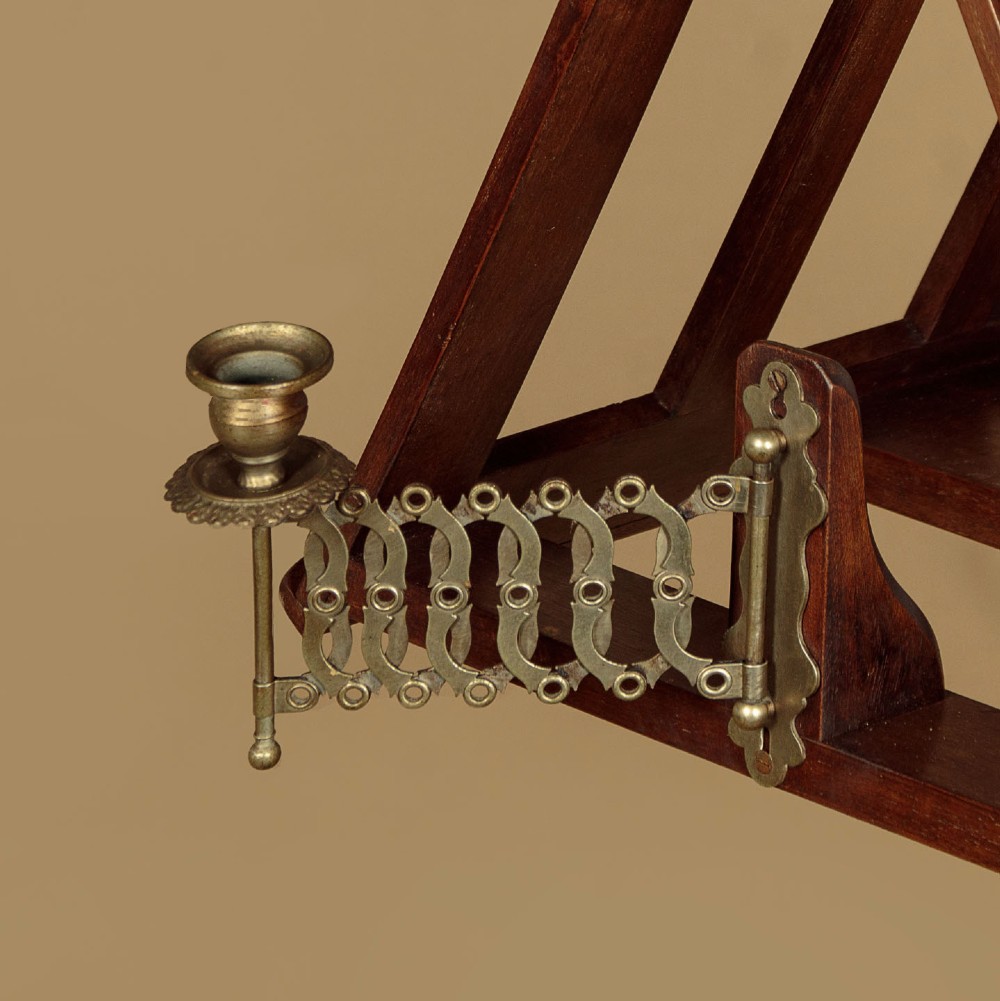 An antique dark mahogany duet music stand with a double-sided slatted rack, twin adjustable brass candle sconces, and a tripod base. View VI