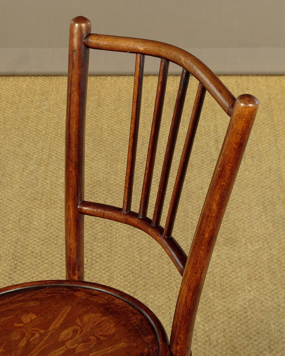 A set of four dark brown bentwood bistro dining chairs with vertical spindle backs, circular wooden seats, and curved legs. View V