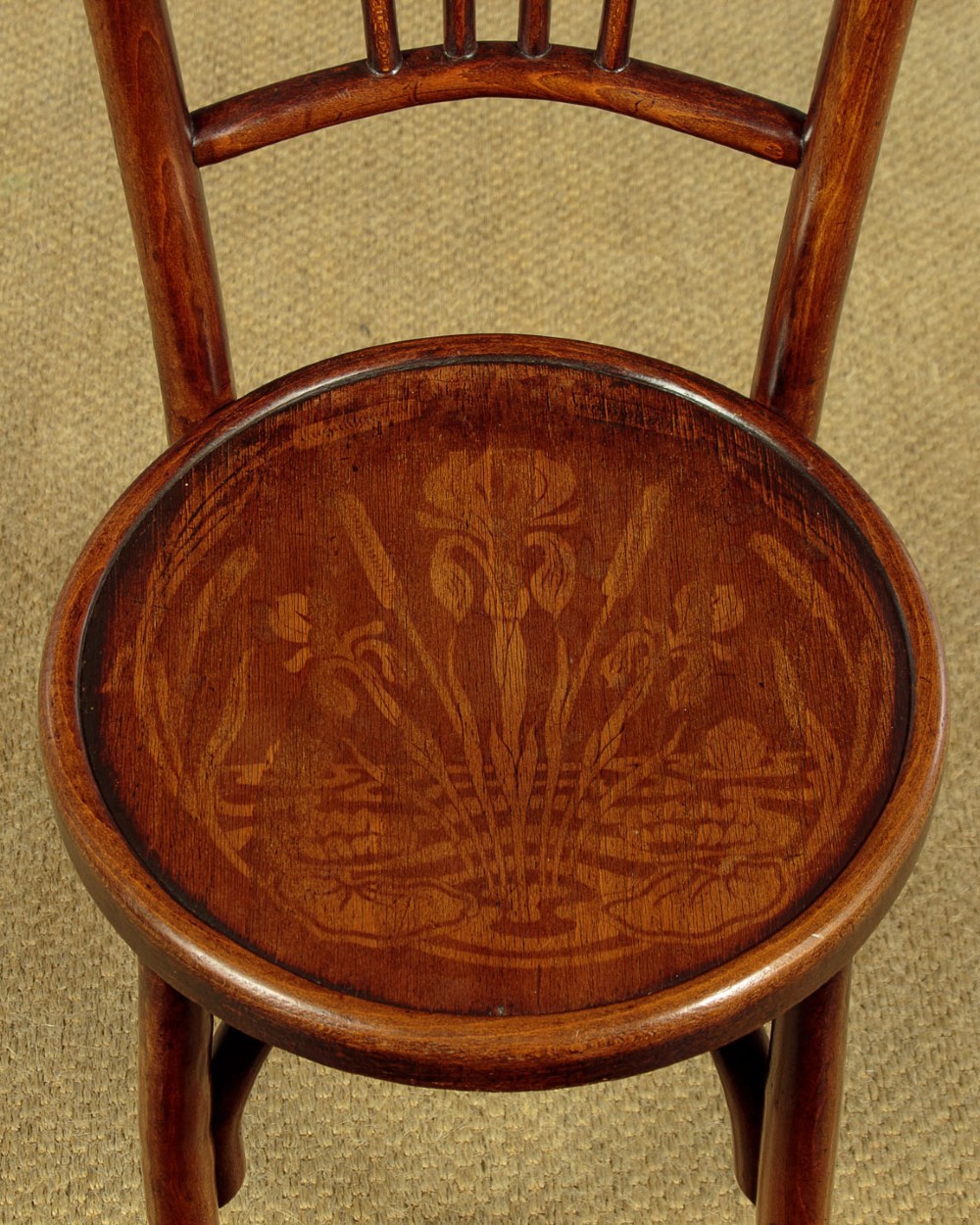 A set of four dark brown bentwood bistro dining chairs with vertical spindle backs, circular wooden seats, and curved legs. View VII