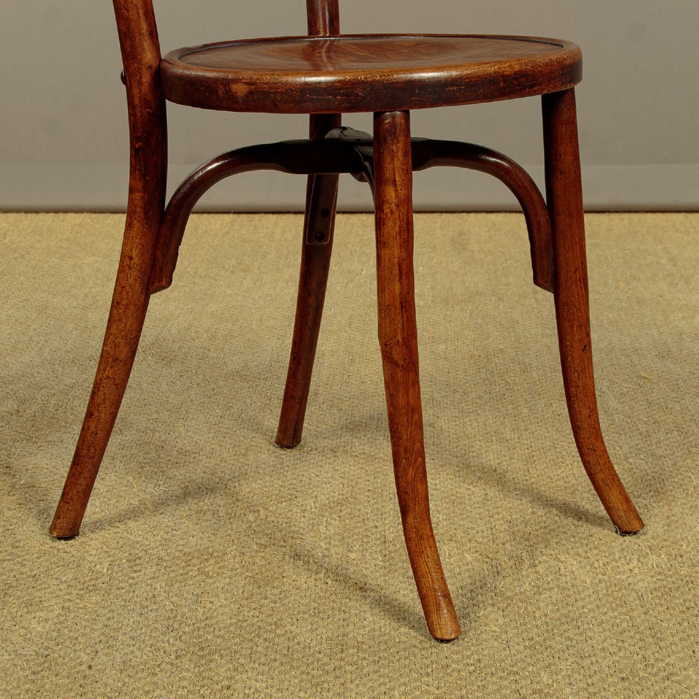 A set of four dark brown bentwood bistro dining chairs with vertical spindle backs, circular wooden seats, and curved legs. View IX