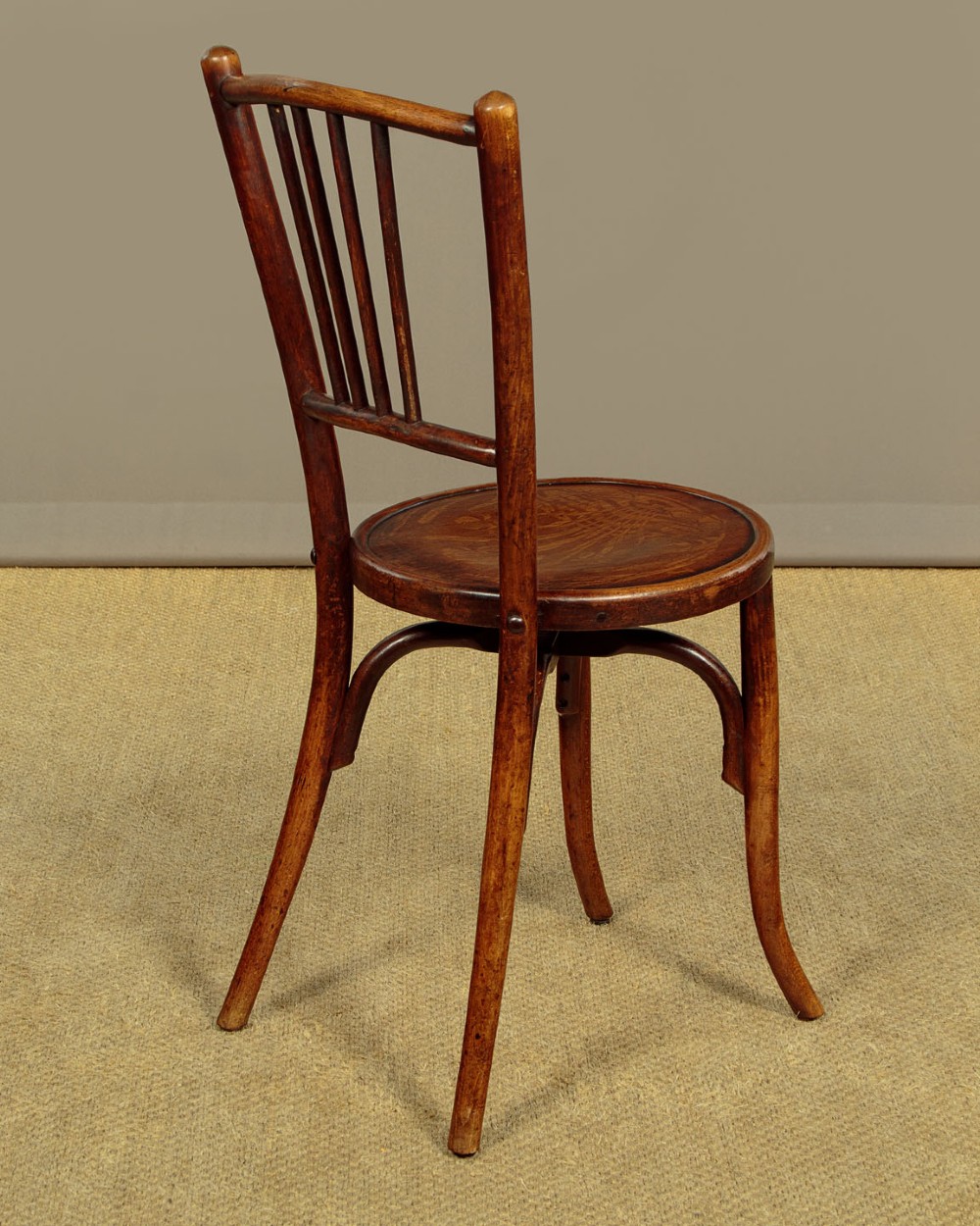 A set of four dark brown bentwood bistro dining chairs with vertical spindle backs, circular wooden seats, and curved legs. View X