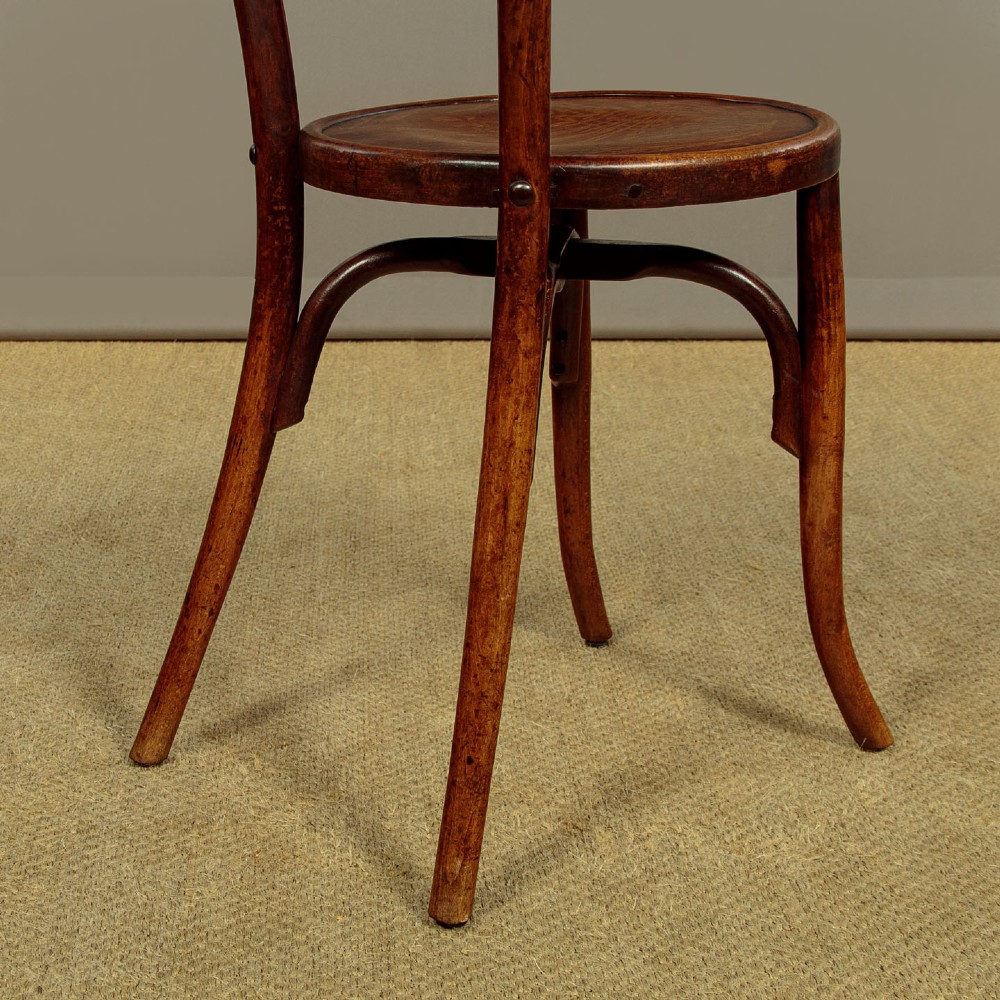 A set of four dark brown bentwood bistro dining chairs with vertical spindle backs, circular wooden seats, and curved legs. View XI