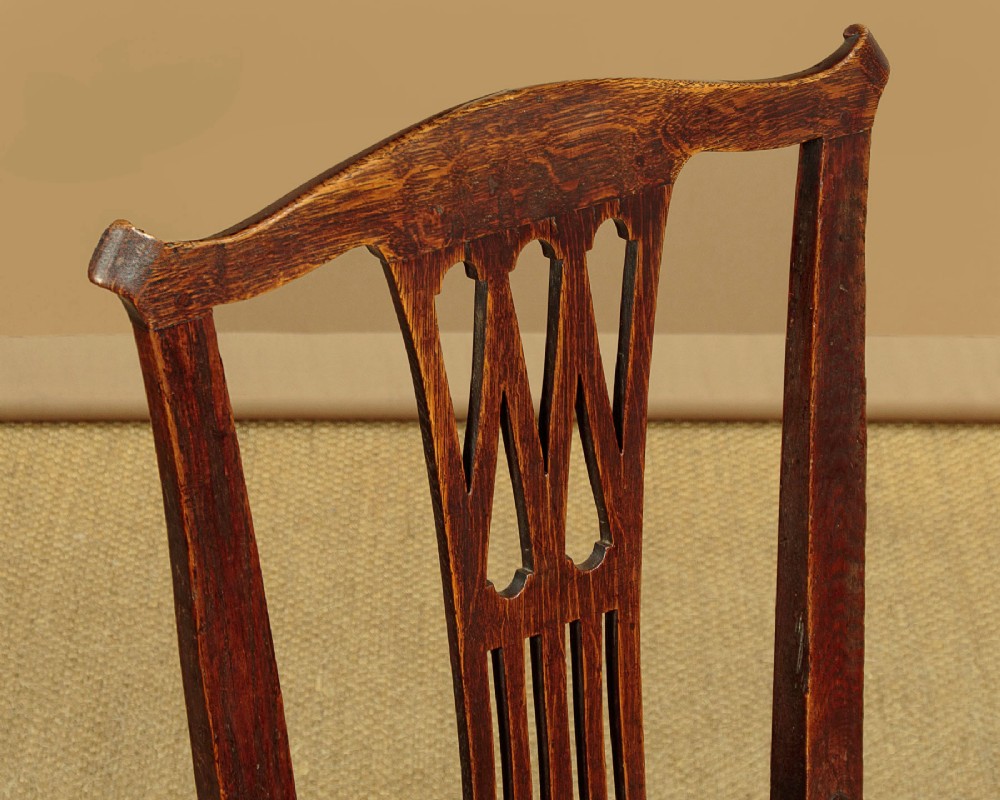 A set of six dark oak Country Chippendale dining chairs featuring pierced splat backs, solid seats, and square legs connected by stretchers. View VI