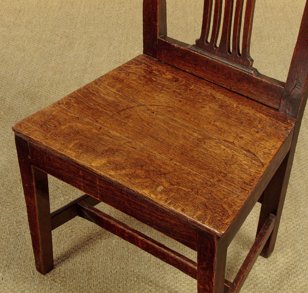 A set of six dark oak Country Chippendale dining chairs featuring pierced splat backs, solid seats, and square legs connected by stretchers. View VIII