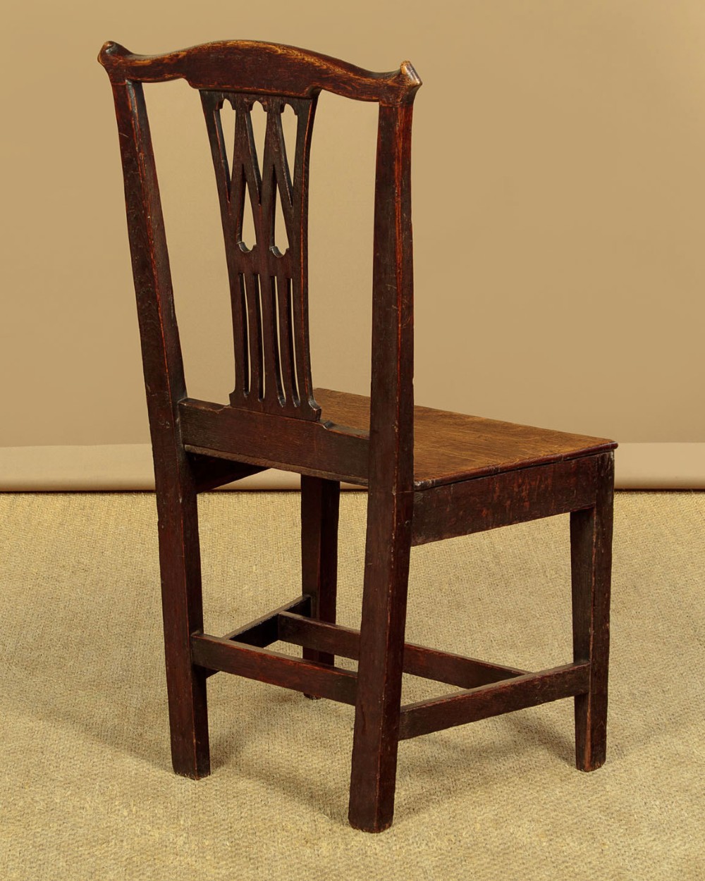 A set of six dark oak Country Chippendale dining chairs featuring pierced splat backs, solid seats, and square legs connected by stretchers. View XI