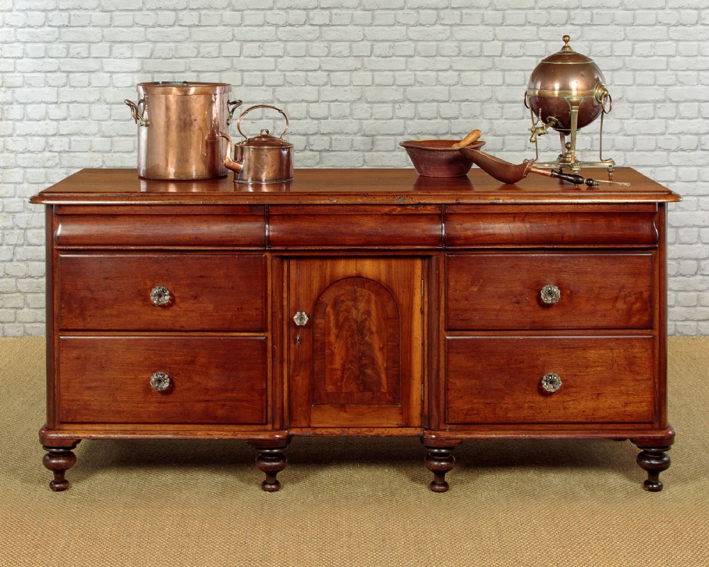 A Victorian walnut sideboard featuring a central arched cupboard door flanked by drawers with faceted glass knobs, set on turned feet. View II