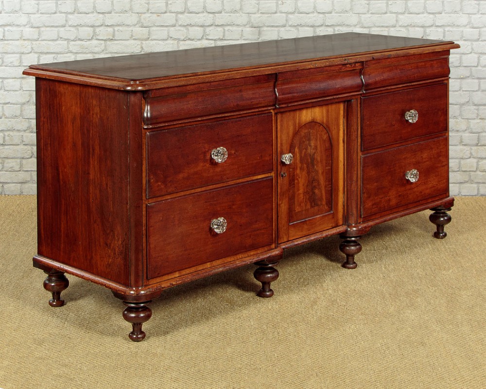 A Victorian walnut sideboard featuring a central arched cupboard door flanked by drawers with faceted glass knobs, set on turned feet. View III