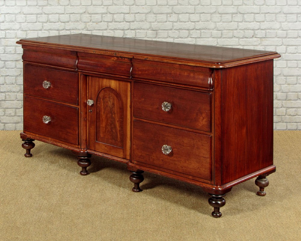 A Victorian walnut sideboard featuring a central arched cupboard door flanked by drawers with faceted glass knobs, set on turned feet. View IV