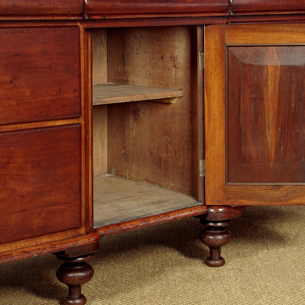A Victorian walnut sideboard featuring a central arched cupboard door flanked by drawers with faceted glass knobs, set on turned feet. View X