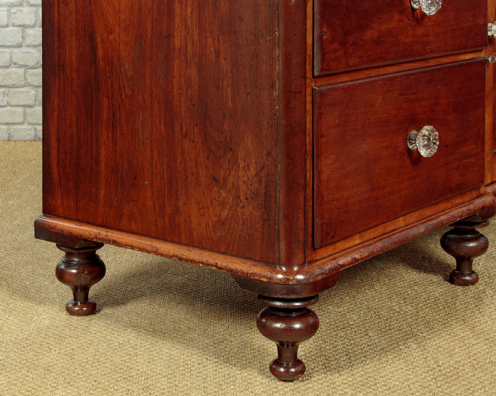 A Victorian walnut sideboard featuring a central arched cupboard door flanked by drawers with faceted glass knobs, set on turned feet. View XII