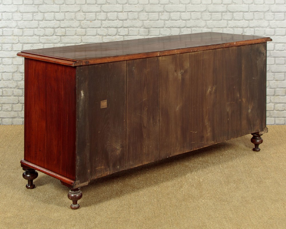 A Victorian walnut sideboard featuring a central arched cupboard door flanked by drawers with faceted glass knobs, set on turned feet. View XIV