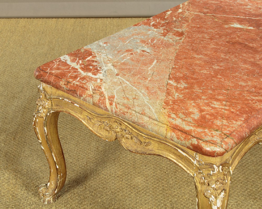 A low rectangular coffee table featuring a pink and red veined marble top supported by a carved giltwood frame with cabriole legs. View VI