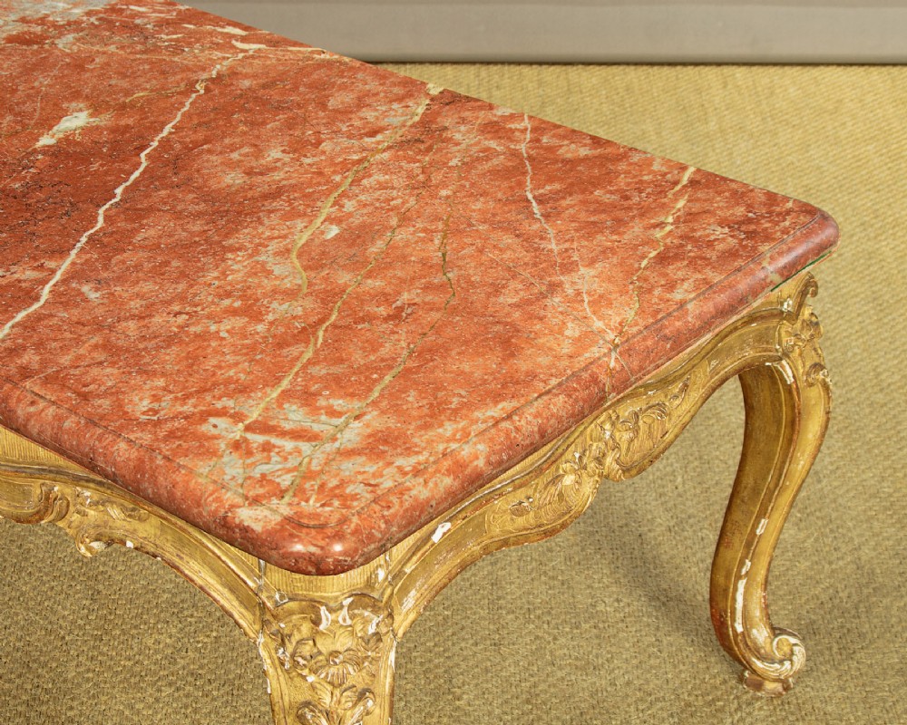 A low rectangular coffee table featuring a pink and red veined marble top supported by a carved giltwood frame with cabriole legs. View VII