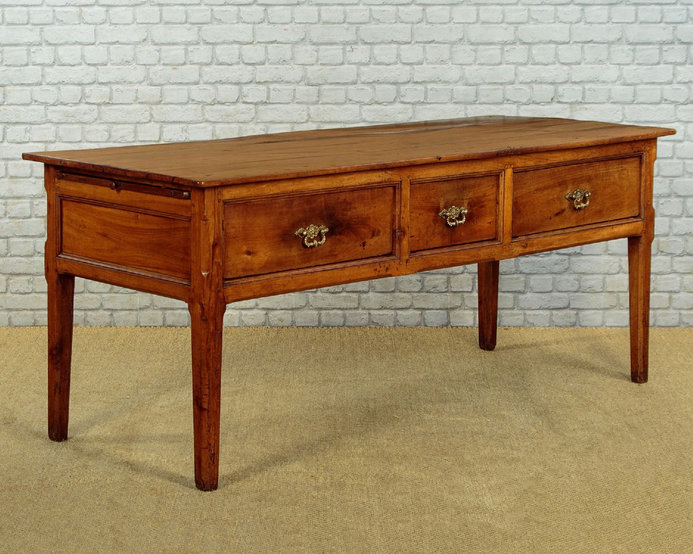 A mid-19th-century French cherry wood kitchen work table featuring three front drawers with brass handles and tapered square legs. View III