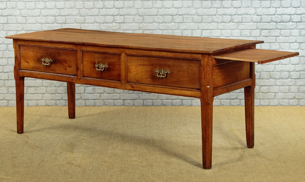A mid-19th-century French cherry wood kitchen work table featuring three front drawers with brass handles and tapered square legs. View V