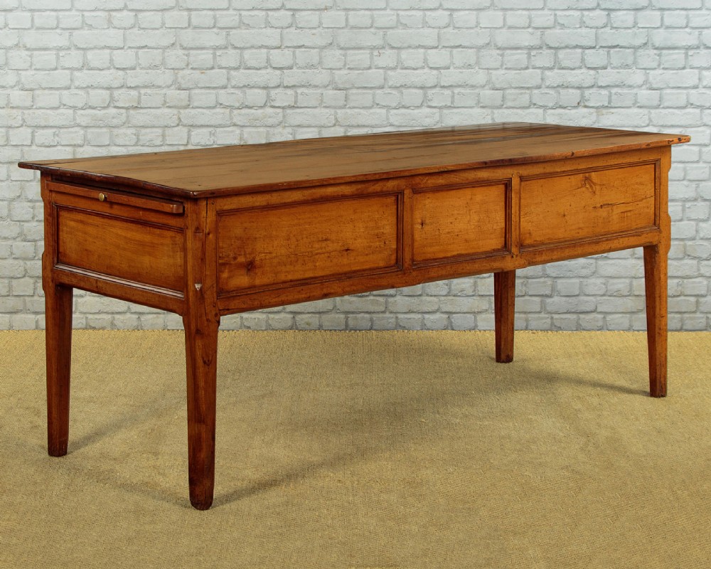 A mid-19th-century French cherry wood kitchen work table featuring three front drawers with brass handles and tapered square legs. View VI