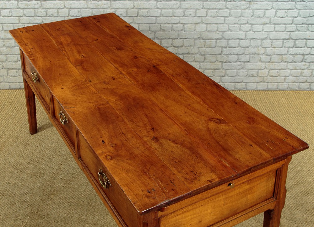 A mid-19th-century French cherry wood kitchen work table featuring three front drawers with brass handles and tapered square legs. View VII