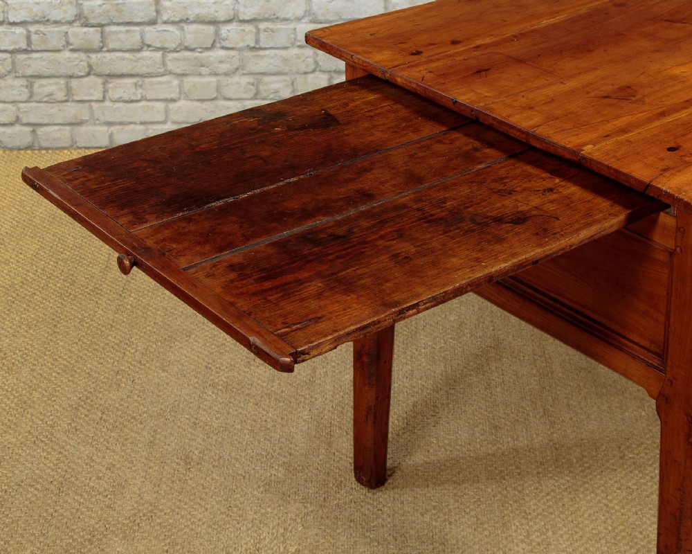 A mid-19th-century French cherry wood kitchen work table featuring three front drawers with brass handles and tapered square legs. View X