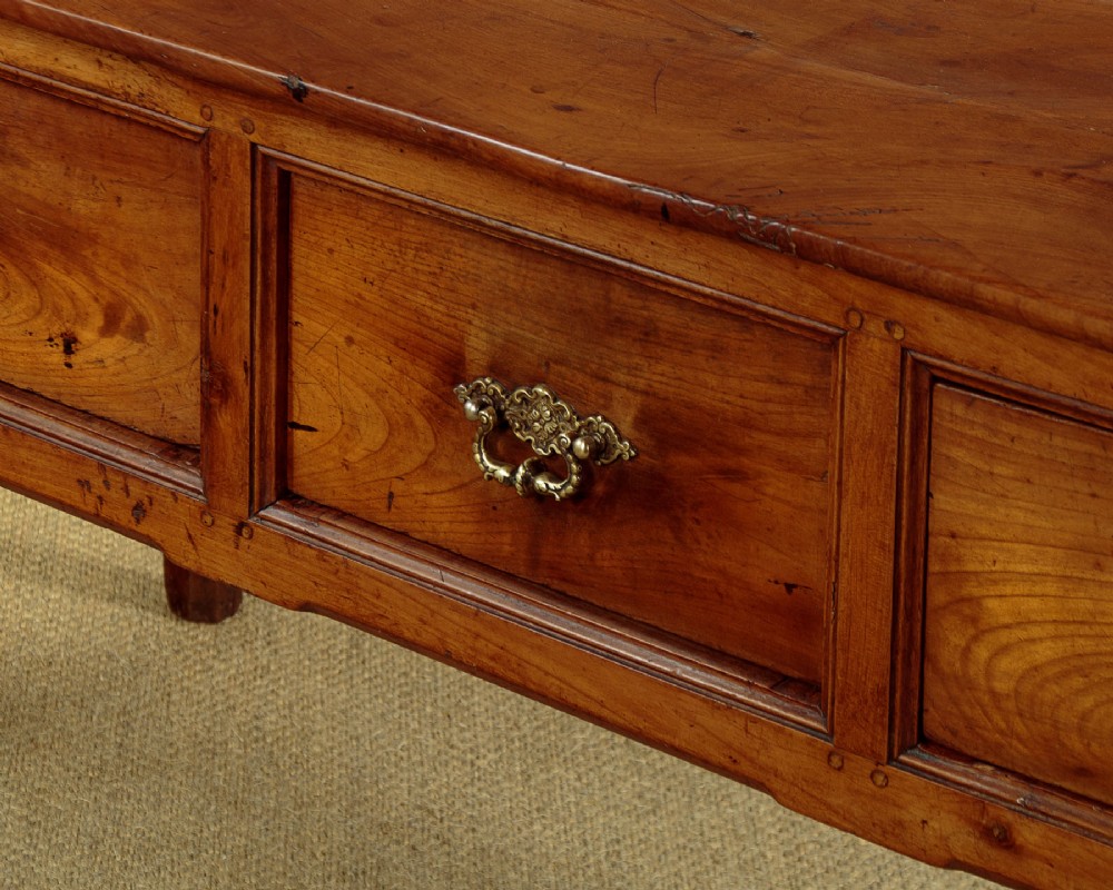 A mid-19th-century French cherry wood kitchen work table featuring three front drawers with brass handles and tapered square legs. View XIII