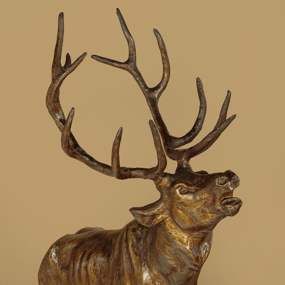 A bronze-patinated spelter sculpture depicting a bellowing stag on a rocky outcrop, mounted on a veined green marble base with a metallic title plaque. View IV