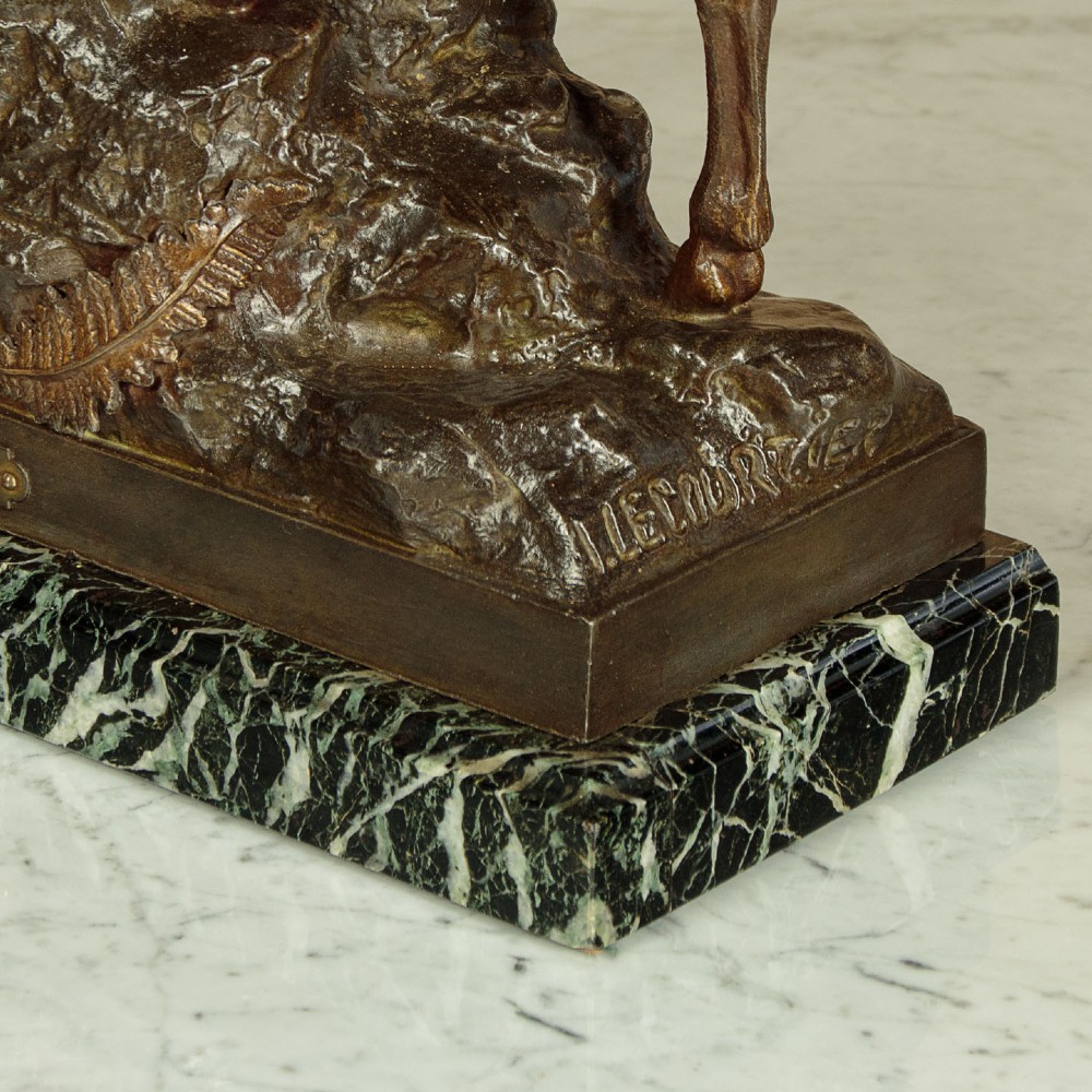 A bronze-patinated spelter sculpture depicting a bellowing stag on a rocky outcrop, mounted on a veined green marble base with a metallic title plaque. View X