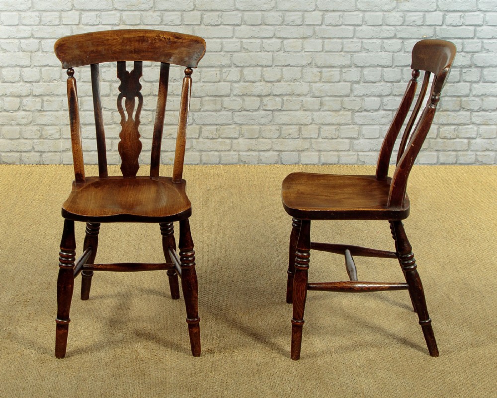 A set of four late 19th-century dark oak dining chairs featuring shaped back rails, pierced splats, contoured wooden seats, and turned legs with stretchers. View II