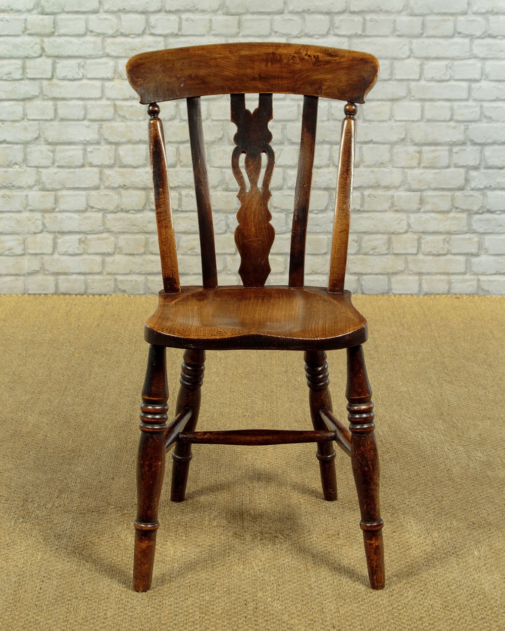 A set of four late 19th-century dark oak dining chairs featuring shaped back rails, pierced splats, contoured wooden seats, and turned legs with stretchers. View IV
