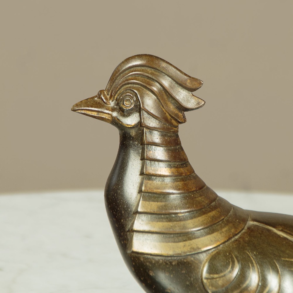 An Art Deco patinated metal sculpture featuring two stylised pheasants mounted on a rectangular black marble base with white veining. View V
