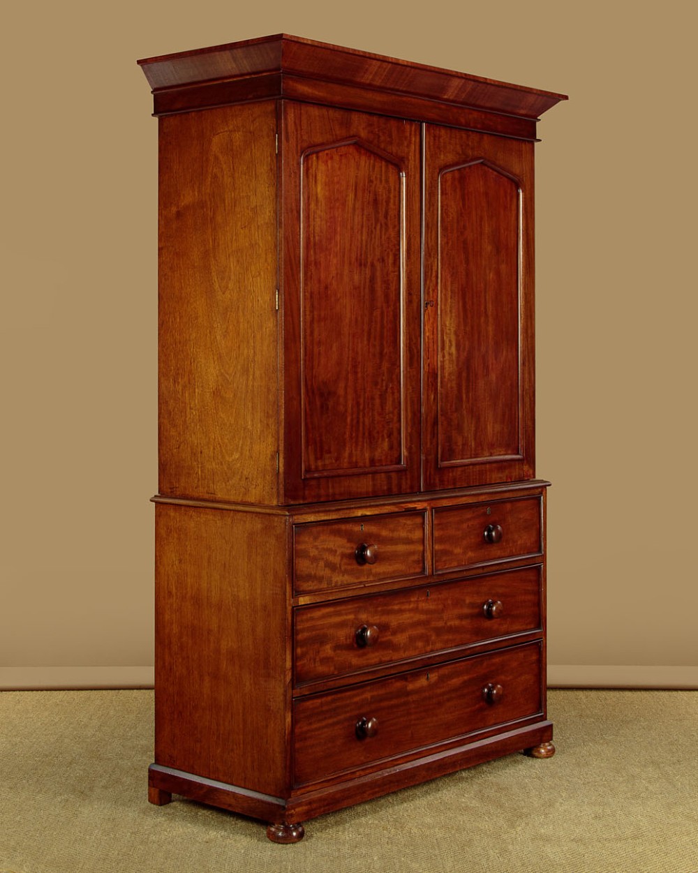 A nineteenth-century mahogany linen press featuring flame mahogany panel doors opening to reveal timber trays above a base of four drawers with turned wooden knobs. View III
