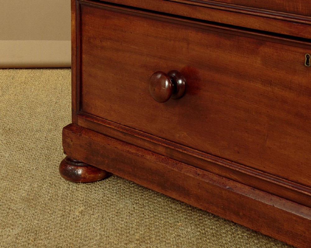 A nineteenth-century mahogany linen press featuring flame mahogany panel doors opening to reveal timber trays above a base of four drawers with turned wooden knobs. View XII