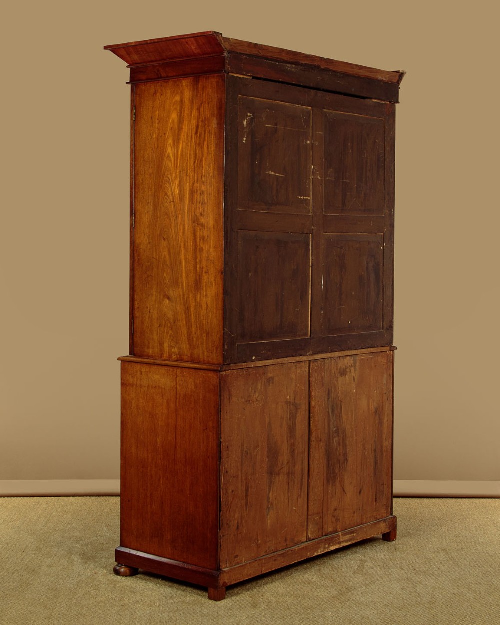 A nineteenth-century mahogany linen press featuring flame mahogany panel doors opening to reveal timber trays above a base of four drawers with turned wooden knobs. View XIV