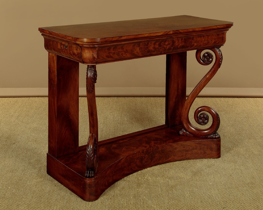 A 19th-century Victorian mahogany console table featuring carved S-scroll front supports and a concave plinth base.