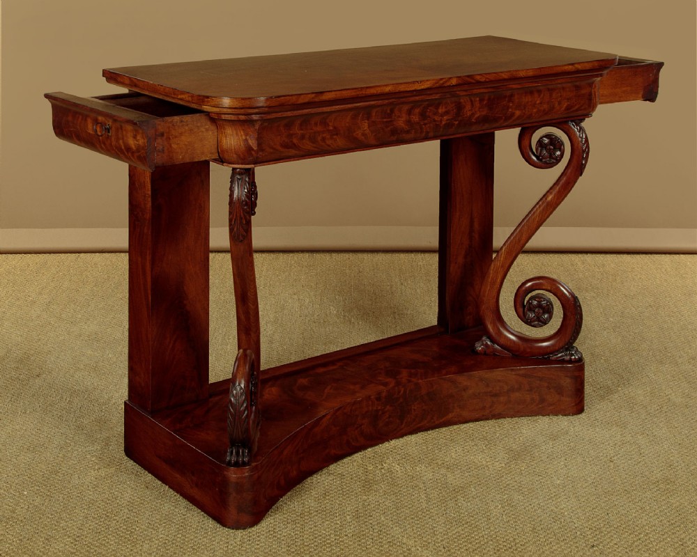 A 19th-century Victorian mahogany console table featuring carved S-scroll front supports and a concave plinth base. View V