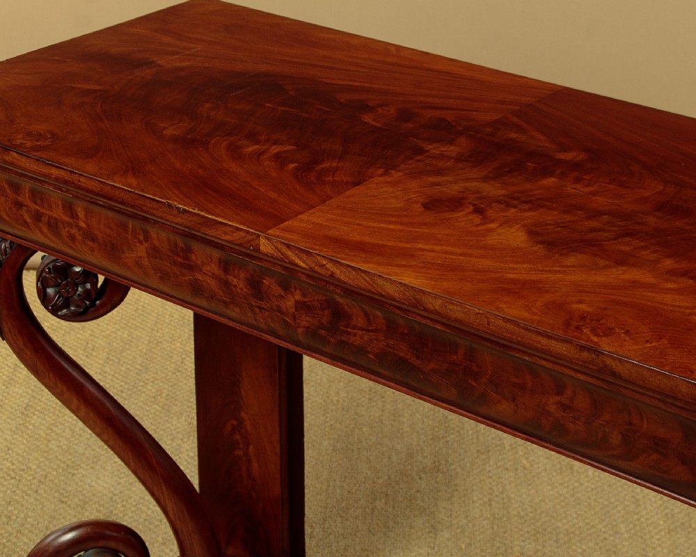 A 19th-century Victorian mahogany console table featuring carved S-scroll front supports and a concave plinth base. View VII
