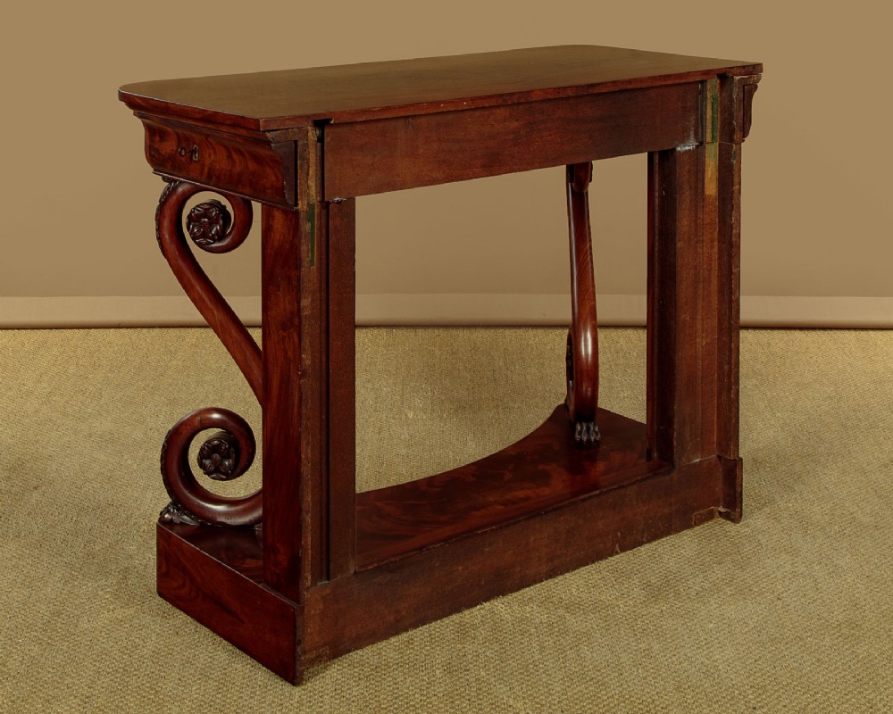 A 19th-century Victorian mahogany console table featuring carved S-scroll front supports and a concave plinth base. View XIV