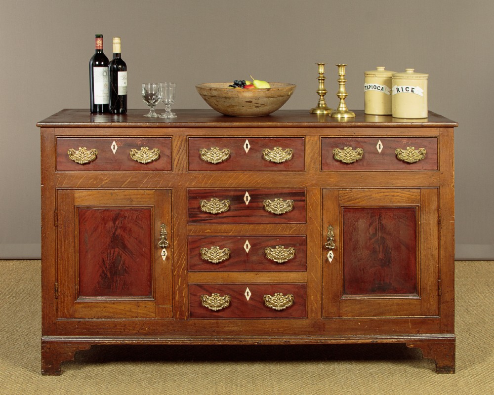 An antique 19th-century painted pine dresser base with central drawers, two side cupboard doors, red painted accent panels, and brass handles. View II
