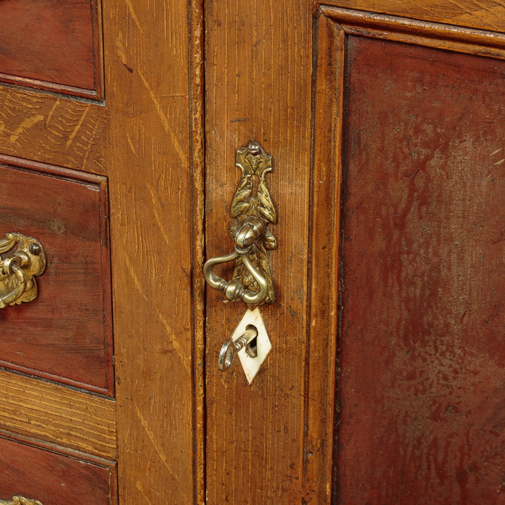 An antique 19th-century painted pine dresser base with central drawers, two side cupboard doors, red painted accent panels, and brass handles. View X