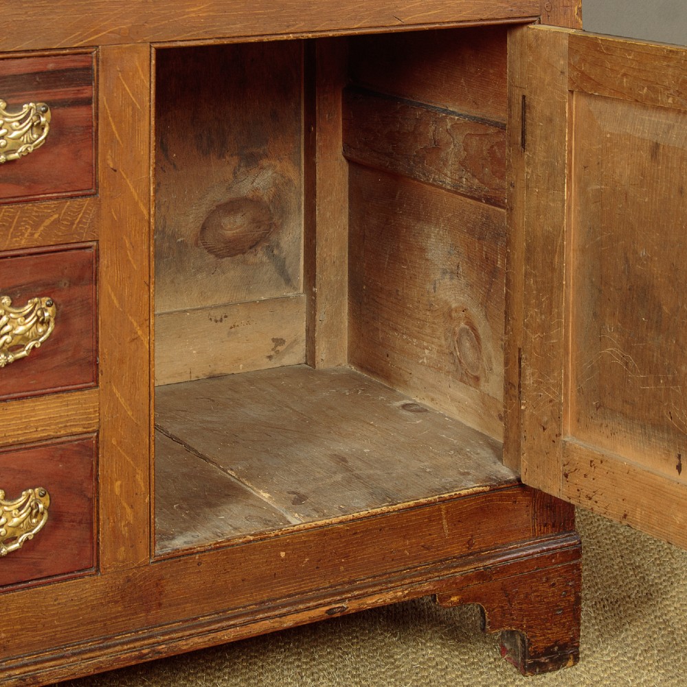 An antique 19th-century painted pine dresser base with central drawers, two side cupboard doors, red painted accent panels, and brass handles. View XI