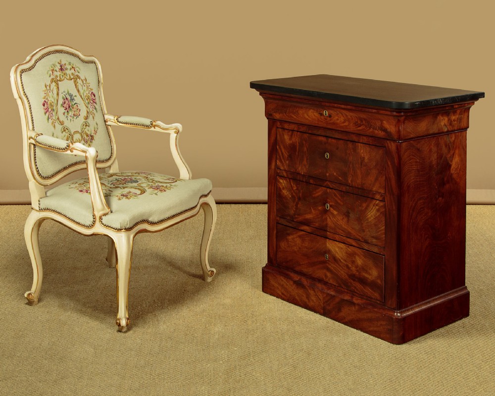 A nineteenth-century flame mahogany commode chest with four drawers, brass escutcheons, a dark slate top surface, and a plinth base. View II